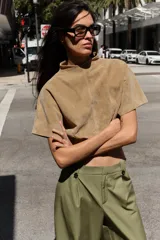 Pantalón de tiro alto con corte recto, bolsillos delanteros y detalle de pinzas con botones en la cintura. Cuenta con cierre frontal de cremallera y gancho metálico.