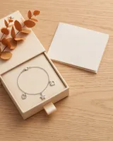 Pulsera de cadena plateada con dijes colgantes de corazón y estrella con incrustaciones de circones.