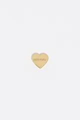 Pendientes tipo broquel con diseño de corazón en acabado metálico plateado y logo grabado en el centro.