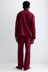 Pijama de dos piezas confeccionado en franela de algodón. Incluye una camisa de manga larga con cuello inglés, botones frontales y bolsillo en el pecho, junto con un pantalón de corte recto con cintura elástica y cordón ajustable.