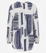 Camisa amplia de viscolino con estampado geométrico en azul marino sobre fondo crudo. Tiene cuello redondo con lazo, mangas largas abullonadas y abotonadura frontal.