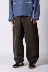 Pantalón de jean con corte balloon, de tiro medio y pernera ancha con volumen. Presenta un lavado tipo oxidado en tono marrón oscuro y costuras laterales marcadas.