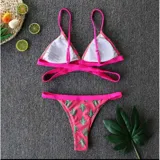 Bikini fucsia con estampado de cactus, compuesto por un corpiño triangular con tiras cruzadas debajo del busto y una bombacha tipo tanga cavada con ribetes fucsias.