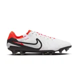 Championes de fútbol Nike Tiempo Legend 10 Pro FG, color blanco con detalles en negro y naranja. Presentan un diseño texturizado en la parte superior, el logo de Nike en negro con borde blanco y suela con tapones para terreno firme.
