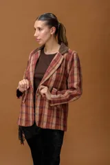 Blazer de tejido con diseño a cuadros en tonos tierra, con solapa de pana en color marrón oscuro, cierre frontal con botón y bolsillos laterales con solapa.
