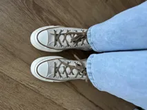 Zapatillas de lona color beige, tipo bota, con cordones marrones, puntera de goma y logo de peach engomado.