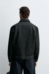 Cazadora de denim de algodón en color negro, de corte regular fit, con cuello solapa, cierre frontal de botones metálicos, mangas largas con puños abotonados y bolsillos laterales de vivo.