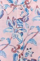 Camisa de manga larga confeccionada en tejido de ramio con estampado floral en tonos azules y violetas sobre fondo rosado. Cuenta con cuello de solapa, cierre frontal de botones y puños con acabado clásico.
