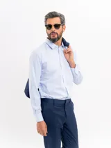 Camisa de vestir de manga larga en color celeste con un sutil patrón de micro cuadros y rayas. Presenta cuello clásico, cierre frontal con botones y puños abotonados.