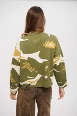 Buzo de tejido de punto con diseño estampado abstracto en tonos verde, blanco y mostaza. Presenta cuello redondo, mangas largas y un corte holgado con ruedo recto.