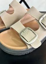 Sandalias de dedo color beige con hebillas plateadas y suela track.