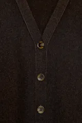 Chaqueta de punto con escote en pico y manga larga. Presenta cierre frontal con botones y costuras verticales decorativas en el frente.
