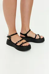 Sandalias negras con plataforma, tiras finas y hebillas metálicas ajustables.