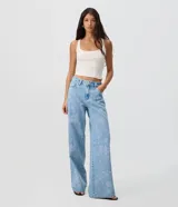 Pantalón wide leg de jean celeste con talle medio y bordados florales en hilo celeste claro a lo largo de las piernas. Cuenta con bolsillos funcionales, pasadores para cinto y cierre frontal con botón y cremallera.