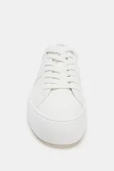 Zapatilla deportiva blanca de mujer, estilo casual con plataforma. Presenta cordones blancos y detalles de costuras y paneles texturizados en el lateral.