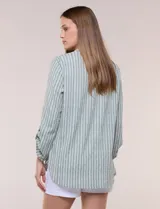Blusa holgada de color verde con diseño de rayas verticales blancas, escote en V con cuello mao y pechera corta con botones. Mangas tres cuartos regulables y bajo redondeado.