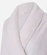 Bata de baño larga de Lov, confeccionada en tejido sherpa de textura aterciopelada. Presenta cuello con solapa, mangas largas, bolsillos frontales y lazo para ajustar en la cintura.