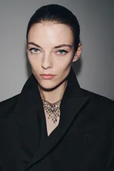 Collar de cadena fina dorada con un colgante en forma de triángulo invertido, compuesto por una red de eslabones circulares engastados con pequeñas piedras brillantes.