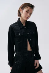 Campera de jean negra con costuras a contra tono y hotfix en tonos de negro, grises y azul.