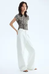 Top de punto suave con estampado de piel de serpiente en tonos grises y blancos, con mangas japonesas, cuello redondo y frunces laterales que crean un efecto drapeado.