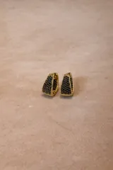 Aros tipo argolla con base metálica dorada e incrustaciones de cristales negros en toda su superficie frontal.
