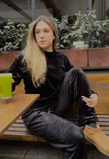 Buzo cropped negro de terciopelo, con cuello alto, mangas largas y cintura ajustable con cordón.