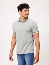 Remera polo de piqué de algodón melange color celeste, con cuello y puños en contraste blanco y azul, cierre frontal con botones y bordado pequeño en el pecho.