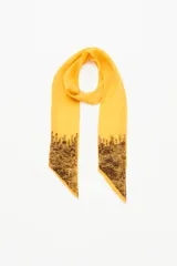 Pañuelo tipo corbatín largo y angosto, confeccionado en símil seda color amarillo, con detalles de lentejuelas bordadas en los extremos.