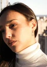 Par de aros dorados tipo argolla con incrustaciones de circonitas y dije colgante de rayo con circonitas.