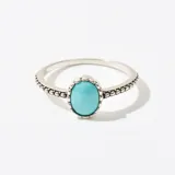 Anillo plateado con piedra turquesa ovalada engarzada.