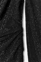 Vestido corto negro con escote barco y tejido drapeado. Presenta una manga corta y una manga larga. Tiene aplicación de strass combinado a tono, forro interior y cierre lateral con cremallera oculta en la costura.