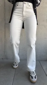 Pantalón de jean color natural, de corte recto con tajos en el lado interno de la pierna y costuras color oro.