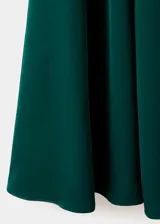 Vestido midi evasé color verde oscuro, de manga larga y cuello redondo, con cierre de cremallera en la parte posterior y detalle de godets.