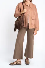 Sobrecamisa de algodón color marrón claro, con cuello camisero y cierre frontal de botones a presión. Presenta detalles de bordado vertical en el frente y en los puños.