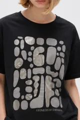 Remera de manga corta de algodón en color blanco, con cuello redondo y diseño holgado. Presenta un estampado frontal con detalle de acabado metálico (foil).