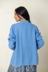 Blazer celeste de lino con corte recto, cuello mao y aplique desflecado en cuello y ruedo.