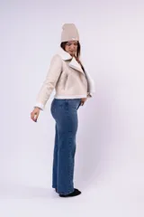 Campera tipo gamulán de cuerina color beige con interior y detalles en corderito blanco. Presenta corte biker, cierre frontal diagonal, bolsillos laterales con cierre y puños con vuelta de corderito.