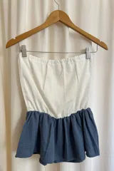 Top strapless de muselina con diseño bicolor, presentando una parte superior en color blanco y un volante inferior en color azul grisáceo.