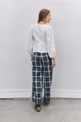 Pantalón sastrero de corte recto y tiro alto con estampado de cuadros escoceses en tonos azul marino, blanco y líneas finas en naranja. Presenta pinzas en la cintura y cierre frontal.