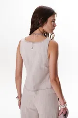 Top color beige claro con escote cuadrado y tirantes anchos. Presenta pespuntes decorativos en un tono más oscuro.