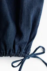 Pantalón tobillero en denim suave de corte holgado con piernas globo, cintura elástica y bolsillos laterales discretos, con abertura ajustable mediante cordón en los bajos.