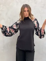 Blusa negra de punto con cuello alto y mangas largas abullonadas con estampado floral.