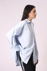 Camisa celeste de corte amplio, con cuello clásico, mangas largas y bolsillo en el pecho.