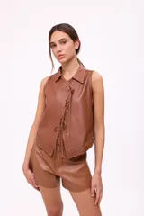 Chaleco de cuero color camel con cuello camisero y cierre frontal de lazos.