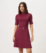 Vestido midi evasé color bordó, con cuello alto, mangas cortas y cintura marcada con cinturón fino removible con hebilla metálica dorada.