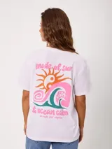 Remera blanca de manga corta de la marca Rusty, con gran estampado en la espalda que combina un sol, una ola y texto con la leyenda 'made of sun & ocean calm'.