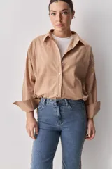 Camisa celeste de corte oversize, con mangas largas, cuello camisero y cierre frontal de botones.