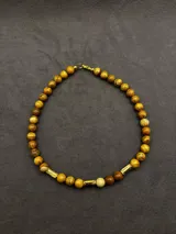 Collar Ound modelo Guayabo, elaborado con cuentas esféricas de piedra en tonos verdosos y marrones, intercaladas con separadores cilíndricos dorados. Cierre de mosquetón dorado.