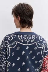 Cardigan de punto con diseño jacquard estilo patchwork en tonos azul, rojo y crema. Presenta un estampado tipo bandana, cuello en V, cierre frontal con botones y mangas largas.