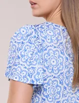 Blusa celeste y blanca con estampado de mandalas, escote redondo amplio con detalle de aplique bordado artesanal en forma de medialuna y mangas cortas estilo mariposa con volados.
